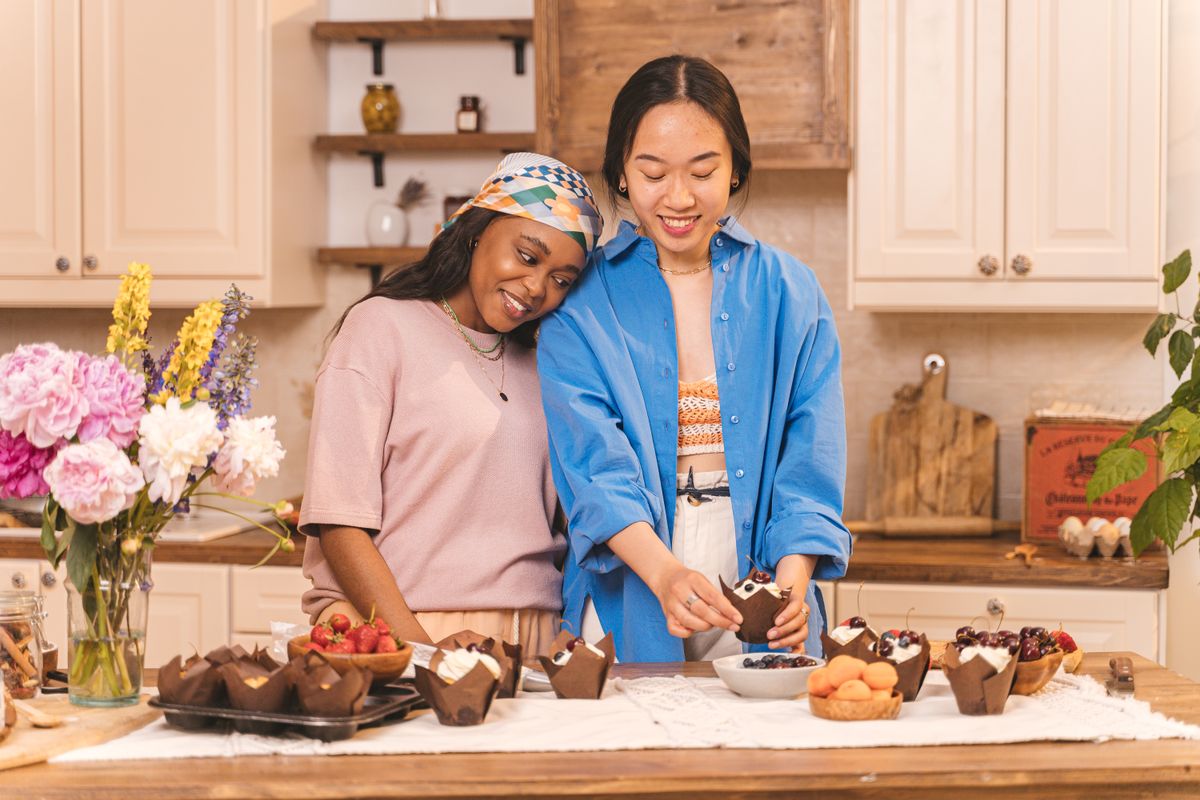 Two bakers decorating a spread of pastries together in a warm kitchen